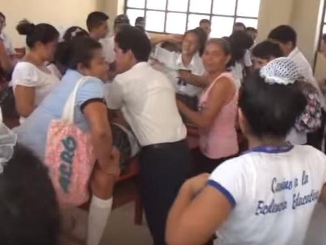 Parents, teachers and classmates restrain ‘possessed’ students on classroom desks at the school.