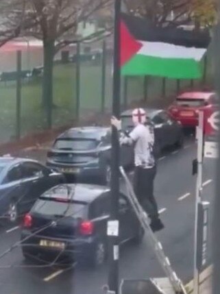 A man wearing a white beanie was filmed removing a Palestinian flag from a lamppost. Picture: Twitter @CrimeLdn