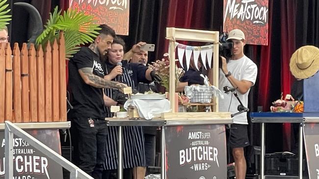 A butcher shows off her cooking creation as part of the ’Butcher Wars’ at Meatstock 2023 at the Melbourne Showgrounds.