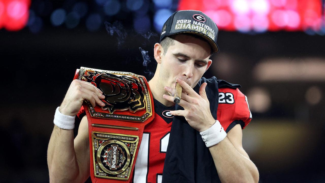 Stetson Bennett #13 of the Georgia Bulldogs celebrates with teammates and a cigar after defeating the TCU Horned Frogs in the College Football Playoff National Championship game.