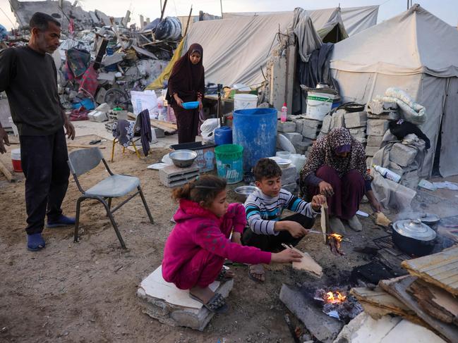 Doctor Khaled Mohammed Abu Jari, 57, (L) and family prepare a meal outside their tent in the northern Gaza Strip. Nations disagree on a ‘realistic’ plan for rebuilding Gaza. Picture: AFP