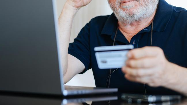 Upset senior elderly man holding credit card by laptop having trouble worry finance safety data or online payment security. Bank client concerned about problem with credit card, financial fraud threat; confusion generic