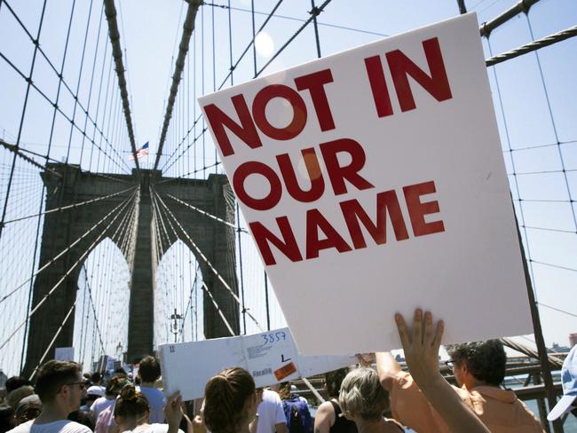 Activists carry signs across the Brooklyn Bridge during a rally to protest the Trump administration's immigration policies. Picture: AP Photo/Kevin Hagen