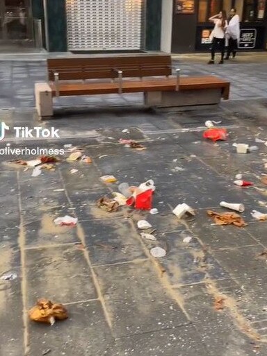 Fast food packaging, paper, plastic bottles and sand can be seen covering the pavement on Cavill Ave. Picture: TikTok/@oliverholmess