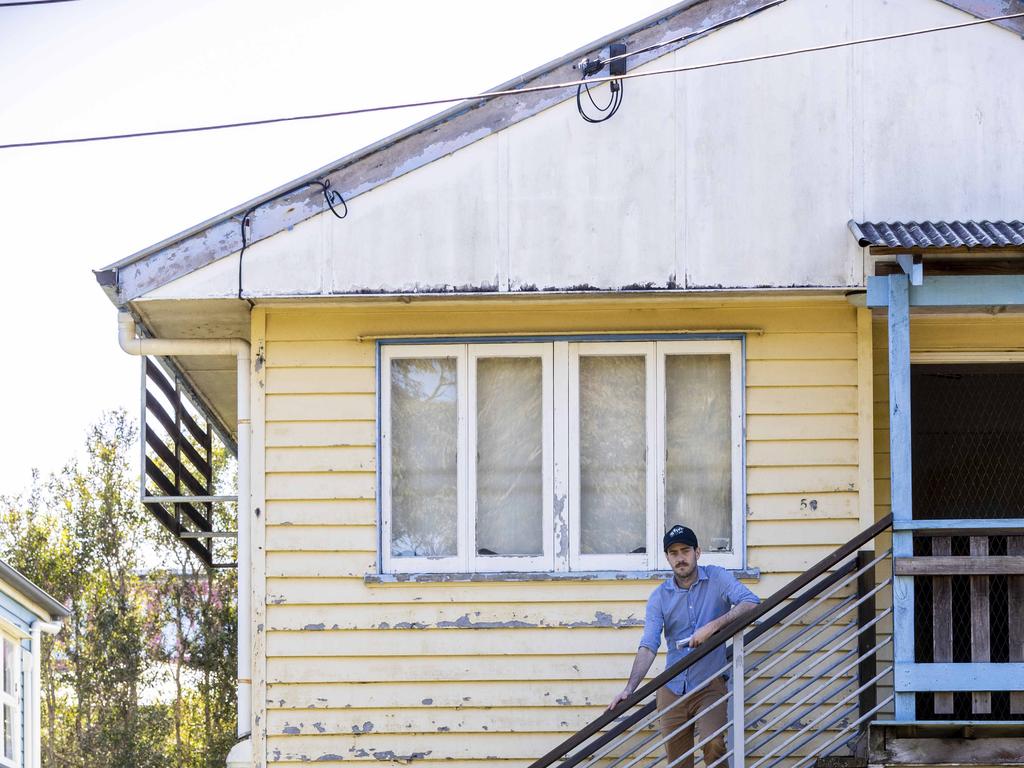 Courier-Mail reporter, Matty Holdsworth, on the stairs of a Tramore Street home, which was smashed by floods. The water level crept up to the third highest step. Picture : Matthew Poon.