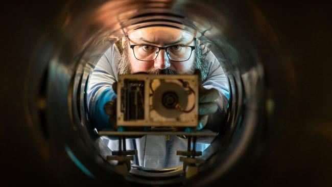 Dr Paddy Neumann from Neumann Space looking down the barrel of a vacuum chamber with the Neumann Drive inside.