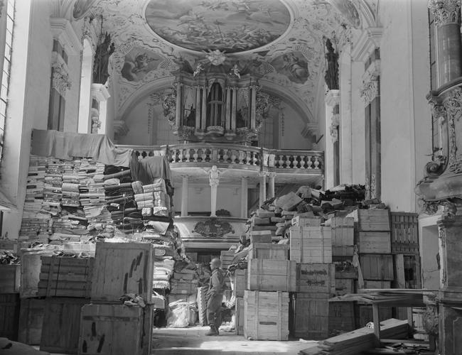 An American soldier inspects stolen art and artefacts stored in a church at Elligen, Germany, April 24, 1945.