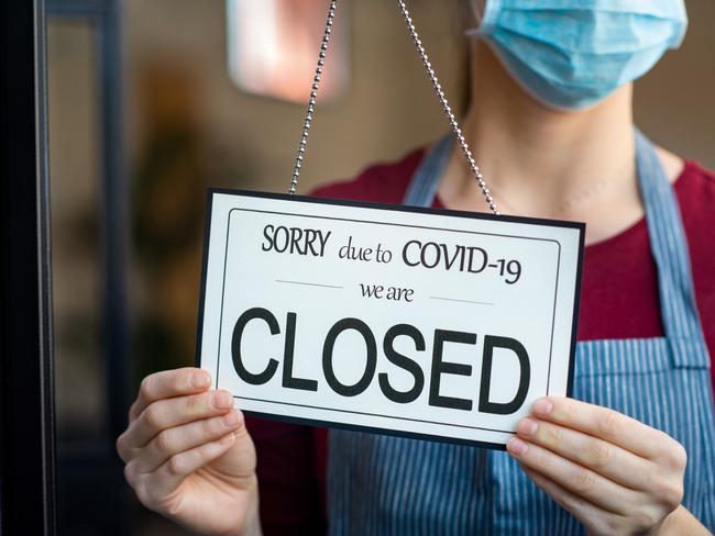 Businesswoman closing her business activity due to covid-19 lockdown. Owner with surgical mask close the doors of her store due to quarantine coronavirus damage. Close up sign of bankrupt business due to the effect of COVID-19 pandemic.