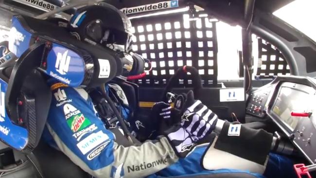 Dale Jr holding the disconnected steering wheel in his left hand, gripping steering column with his right.