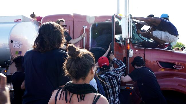 Protesters jump into the cabin of the truck that was driven into the protest. Picture: Reuters