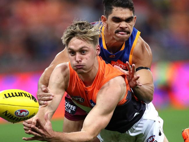 Giants Jackson Hatley handballs ahead of Brisbane's Charlie Cameron during the AFL match between the GWS Giants and Brisbane Lions at Giants Stadium. Picture. Phil Hillyard