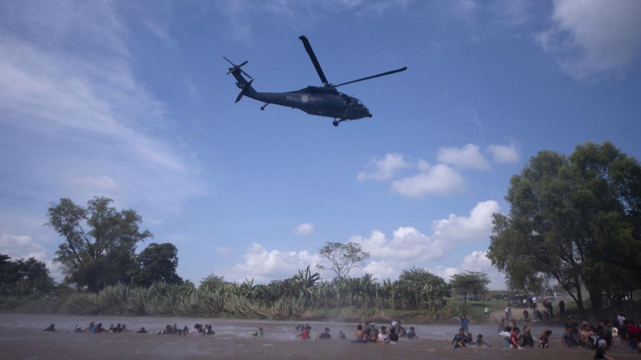 A Mexican Federal Police helicopter flies close to the Suchiate River that connects Mexico and Guatemala, to create a downwash force to discourage migrants from crossing. Picture: Santiago Billy/AP