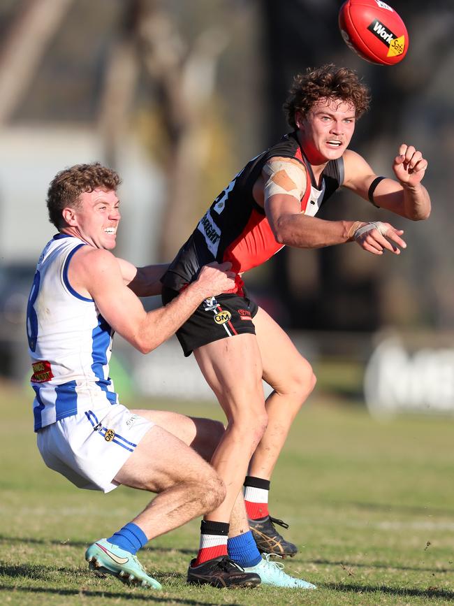 Myrtleford’s Thomas Cappellari gets his handball away despite pressure from Corowa-Rutherglen’s Darcy Melksham.
