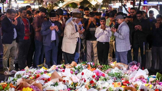 Members of the Ahmadiyya Muslim Community of Australia offer prayers in front of flowers left outside the Westfield Bondi Junction shopping mall in Sydney on April 14. Picture: David Gray/AFP