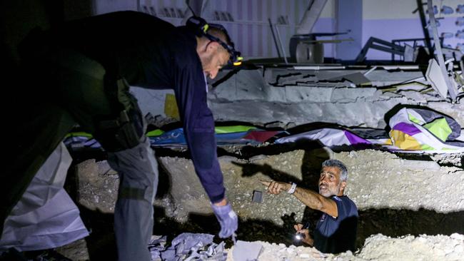 Members of Israel's Home Front Command and police forces inspect a crater left by an exploded projectile. Picture: AFP