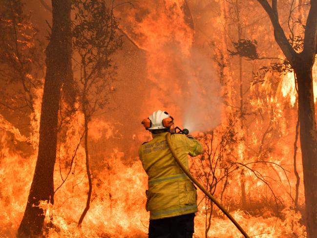 This file photo taken on December 10, 2019 shows a firefighter conducting back-burning measures to secure residential areas from encroaching bushfires in the Central Coast, some 90-110 kilometres north of Sydney. - Climate change is already buffeting Australia with more extreme bushfires, droughts and cyclones -- and the fossil-fuel reliant country should brace for worse to come, according to Australia's top science and weather agencies on November 13, 2020. (Photo by Saeed KHAN / AFP)