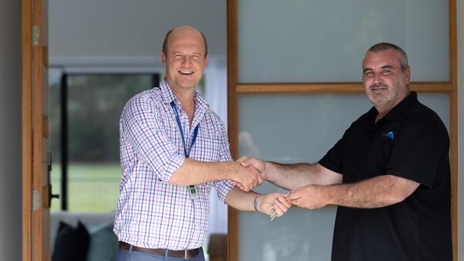 Simon Jarvis from the Mater Prize Home team hands Aaron Stewart the keys to his new home at Bribie Island