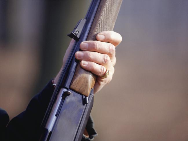 Man holding shotgun, mid section, close-up of hand. Gun. Rifle. Generic image.