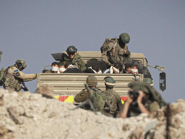 Israeli soldiers detain blindfolded Palestinian men in a military truck while watching Palestinians (not pictured) fleeing the fighting in war-torn Gaza walk by on a road in the Zeitoun district in southern Gaza Strip. Picture: AFP