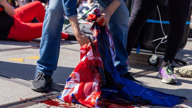 The Australian flag is cut up and has mock blood poured over it during a protest last year in Melbourne. Picture: Getty Images