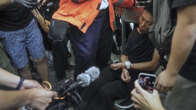 Cameramen and photographers film a detained man, who protesters claimed was a police officer from mainland China, on a luggage trolley during a demonstration at the airport. Picture: AP