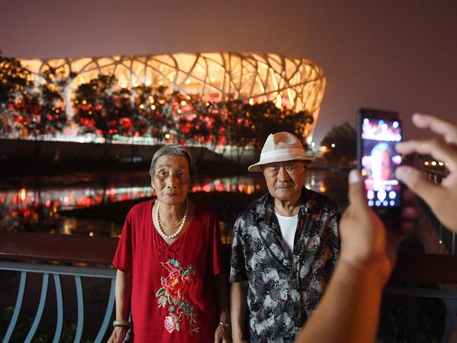 A couple pose for a photo in front of the stadium known as the Bird’s Nest.