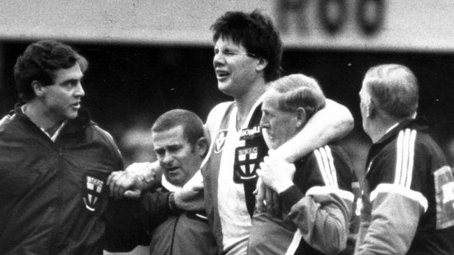 A groggy Danny Frawley is helped off the ground by trainers after being concussed.