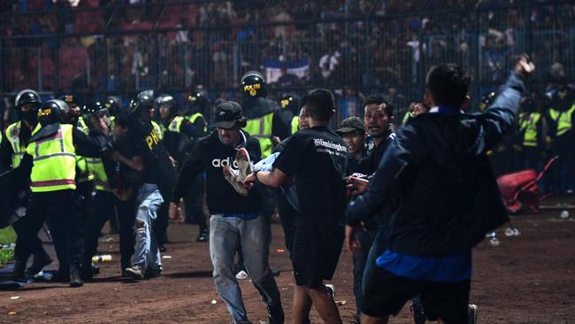 Police and football supporters help the injured following a stampede at a football match in East Java. Picture: AFP
