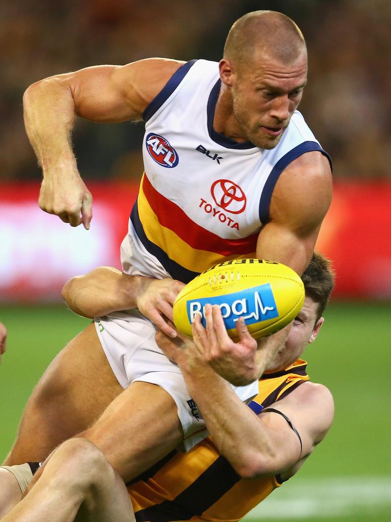 2016 - There is less hair and there are more muscles, but the tough attitude Scott Thompson showed in his early days of AFL footy remain as he takes on Hawk Liam Shiels at the MCG. Picture: Quinn Rooney (Getty Images)