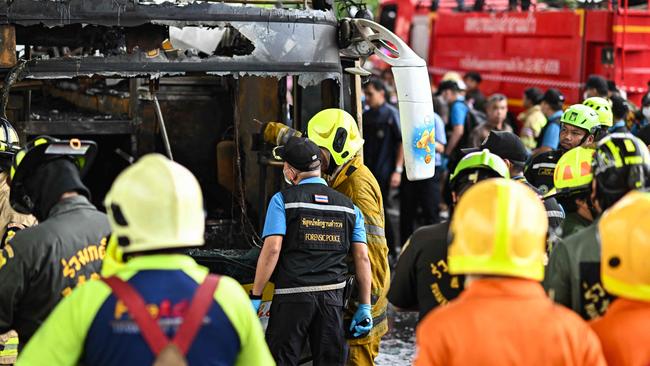 Firefighters and a forensic police officer inspect what’s left of the bus. Picture: AFP