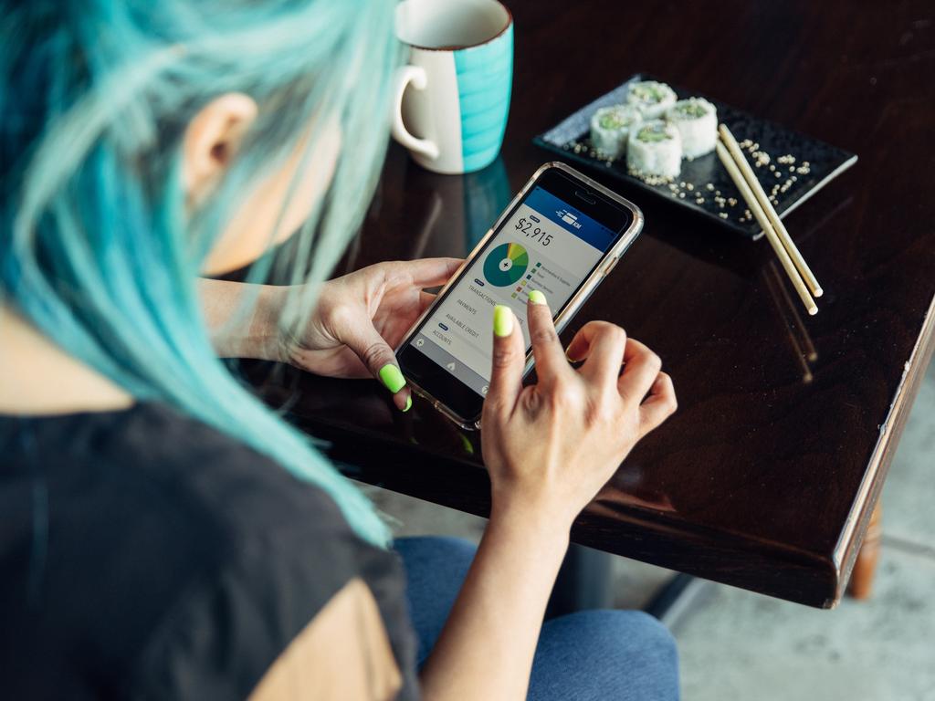 A Hispanic woman of the Millennial Generation is looking at her financial statement while eating lunch at a local sushi restaurant. She is using her bank's app to balance her monthly budget. Image taken in Utah, USA.