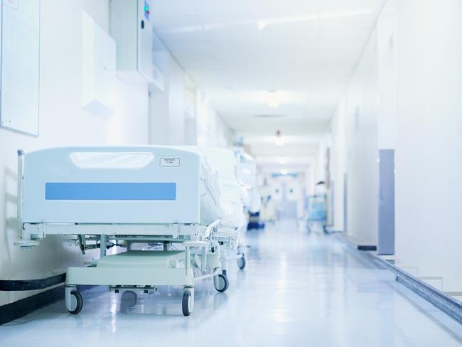 Shot of a hospital bed in an empty corridor of a modern hospital. Photo: iStock