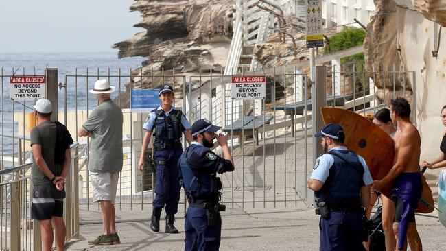 NSW Police officers move people on who were sitting or standing around the Bronte Beach area. Picture: Toby Zerna