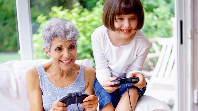 View of a girl (8-10) playing a video game with her grandmother. Generic image.