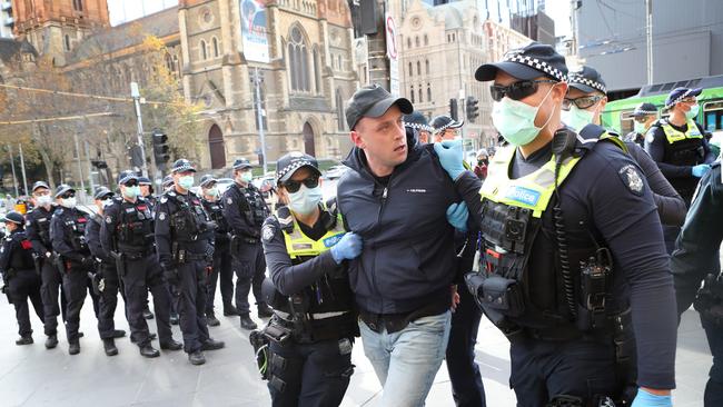 Police detain a man during an anti-lockdown protest outside Flinders Street Station in Melbourne on Saturday. Picture Rebecca Michael. Morgan C Jonas