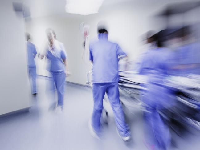 Doctors and nurses pulling hospital trolley,