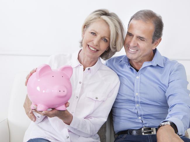 Happy Mature Couple Calculating Coin In The Piggybank. Budget management and savings. For the Good Life feature Wk 43 budgeting.