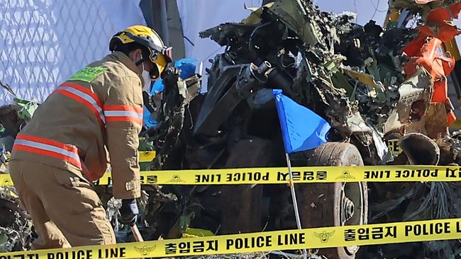 A firefighter works near a wrecked landing gear at the scene where a Jeju Air Boeing 737-800 series aircraft crashed and burst into flames at Muan International Airport. Picture: Yonhap/AFP