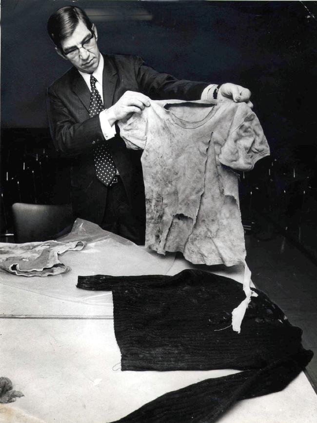 Detective sergeant Ron J Redmond displays some of the garments found near the skeleton found under the Sensible Creek railway bridge west of Charters Towers on November 15, 1972. They include a man's singlet size SM. The skeleton was identified as Robin Jeanne Hoinville-Bartram (19) who had been travelling with Anita Cunningham.