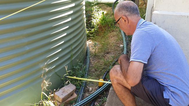 Branko Soda measures the rainwater tank put next to his home. Picture: Colin James