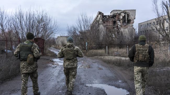 Ukrainian soldiers walk past destroyed buildings in Marinka, Ukraine in December. Picture: Getty Images