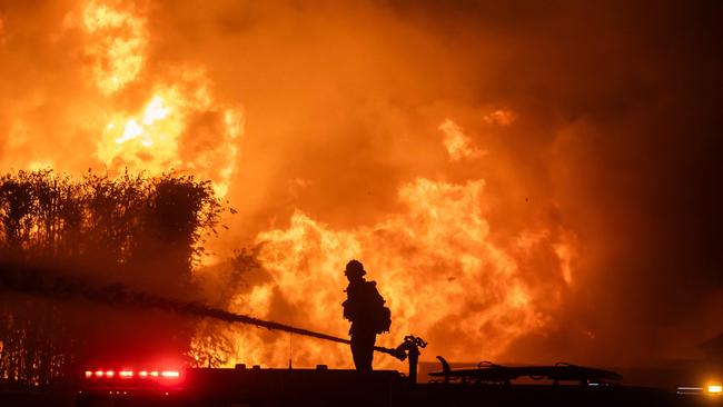 A firefighter stands on top of a fire truck to battle the Palisades fire, which has destroyed the celebrity area. Picture: Getty Images via AFP