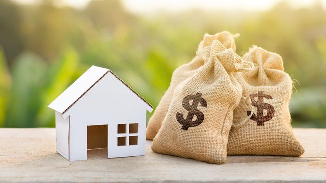 Loan and House concept. Money bags put near house on woodle desk at sunset and green nature background