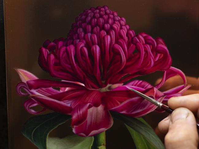 Artist Sebastian Galloway adds the finer details to his floral paintings on copper which form part of his latest exhibition Suspended in Bloom. Picture: Supplied