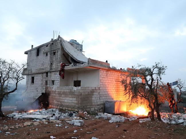 Red tape is extended around the house and objects are set on fire, in which the leader of Islamic State (IS) group Amir Mohammed Said Abd al-Rahman al-Mawla died, in the town of Atme in Syria's northwestern province of Idlib, during an overnight raid by US special forces, on February 3, 2022. - US President Joe Biden said today, a global "terrorist threat" was removed when the head of the Islamic State blew himself up after US special forces swooped on his Syrian hideout in an "incredibly challenging" nighttime helicopter raid. (Photo by Abdulaziz KETAZ / AFP)