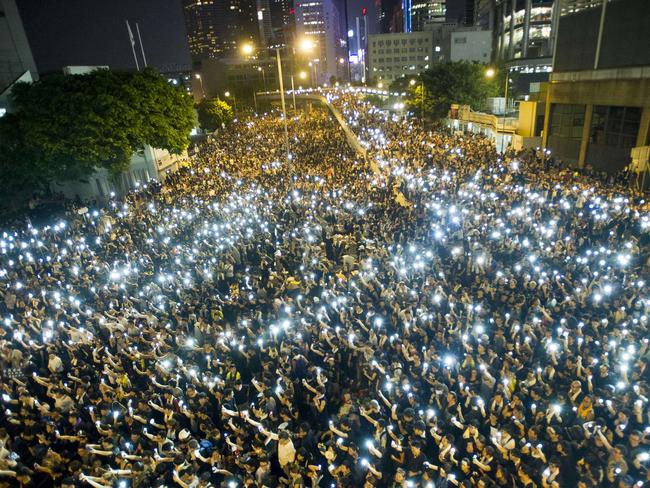 TOPSHOTS Protestors and student demonstrators hold up their cellphones in a display of solidarity during a protest outside the headquarters of Legislative Council in Hong Kong on September 29, 2014. Hong Kong has been plunged into the worst political crisis since its 1997 handover as pro-democracy activists take over the streets following China's refusal to grant citizens full universal suffrage. AFP PHOTO / XAUME OLLEROS