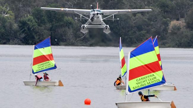 A Sydney Seaplanes Cessna Caravan takes off over a group of somewhat concerned-looking young sailors on Canberra’s Lake Burley Griffin on Tuesday. Picture: AAP