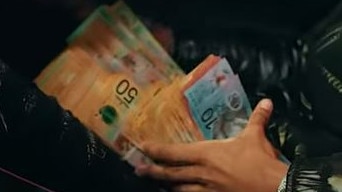 A member of the gang flashes a wad of cash in one of the music videos. Picture: Supplied