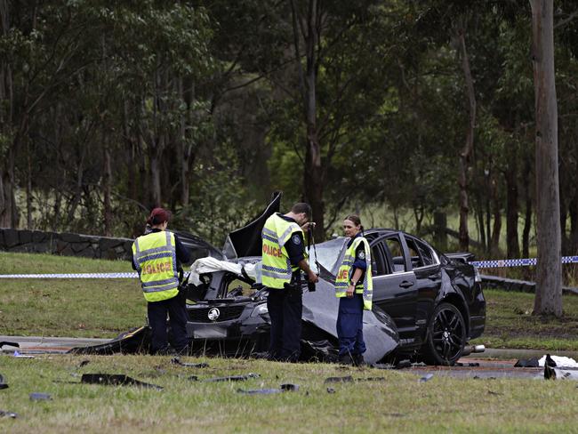 Police look over the crime scene where the fatal car crash occurred at the intersection of Cowpasture Rd and the Horsley Drive. Picture: Adam Yip