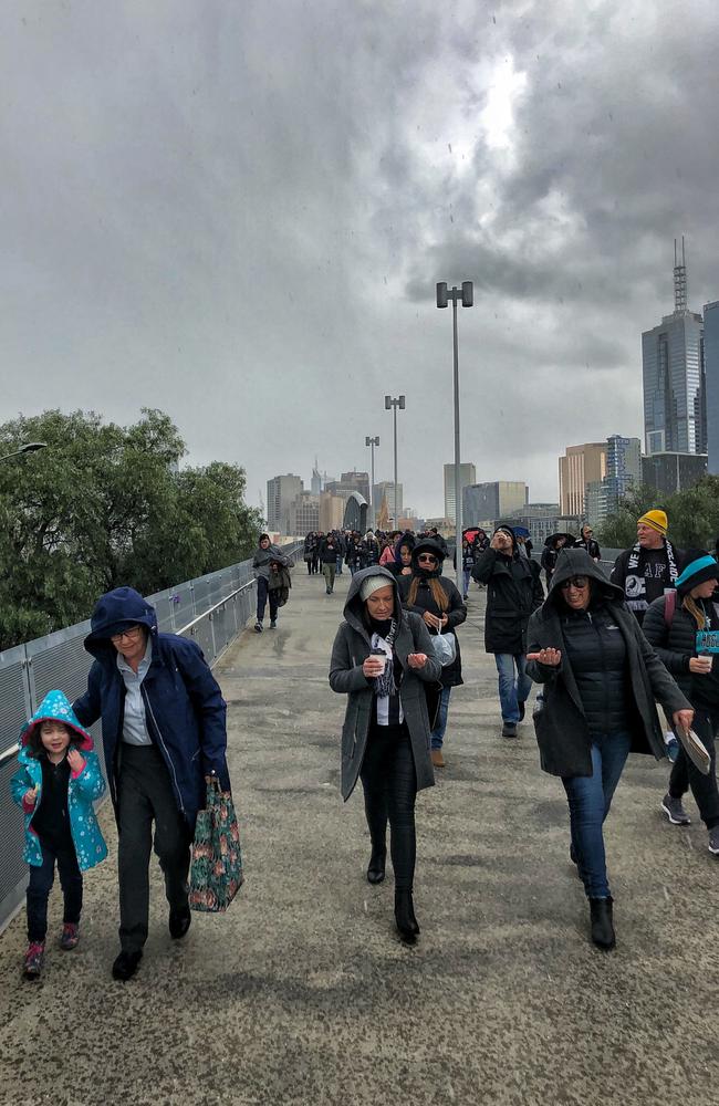 Crowds heading towards the MCG yesterday get caught in a hailstorm. Picture: Jason Edwards